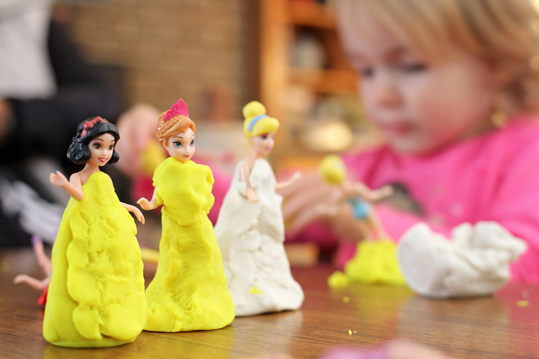 Child molds princess bodies out of clay.