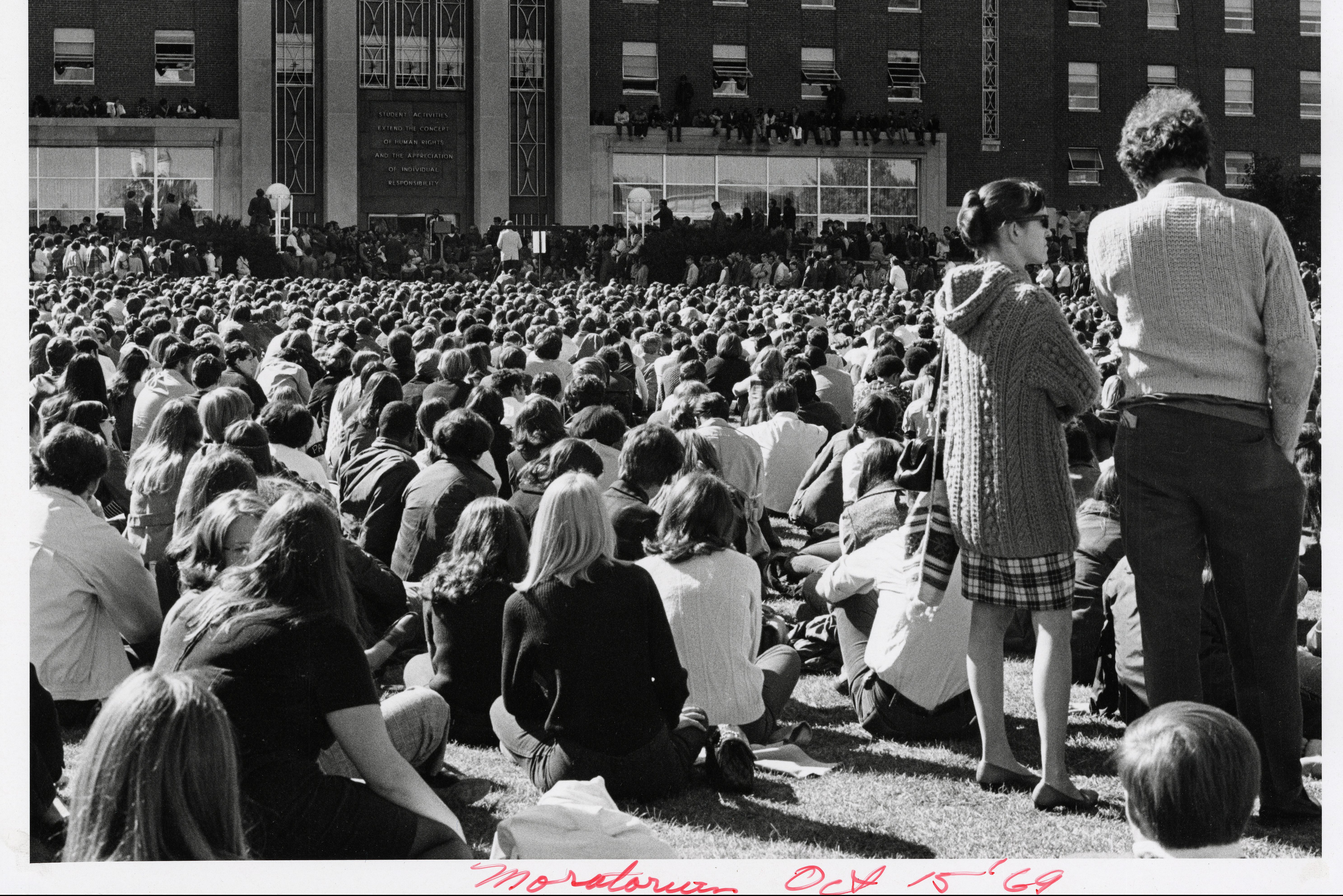 Black and white photo showing a crowd of people listening to speakers in front of the UConn Student Union in 1969