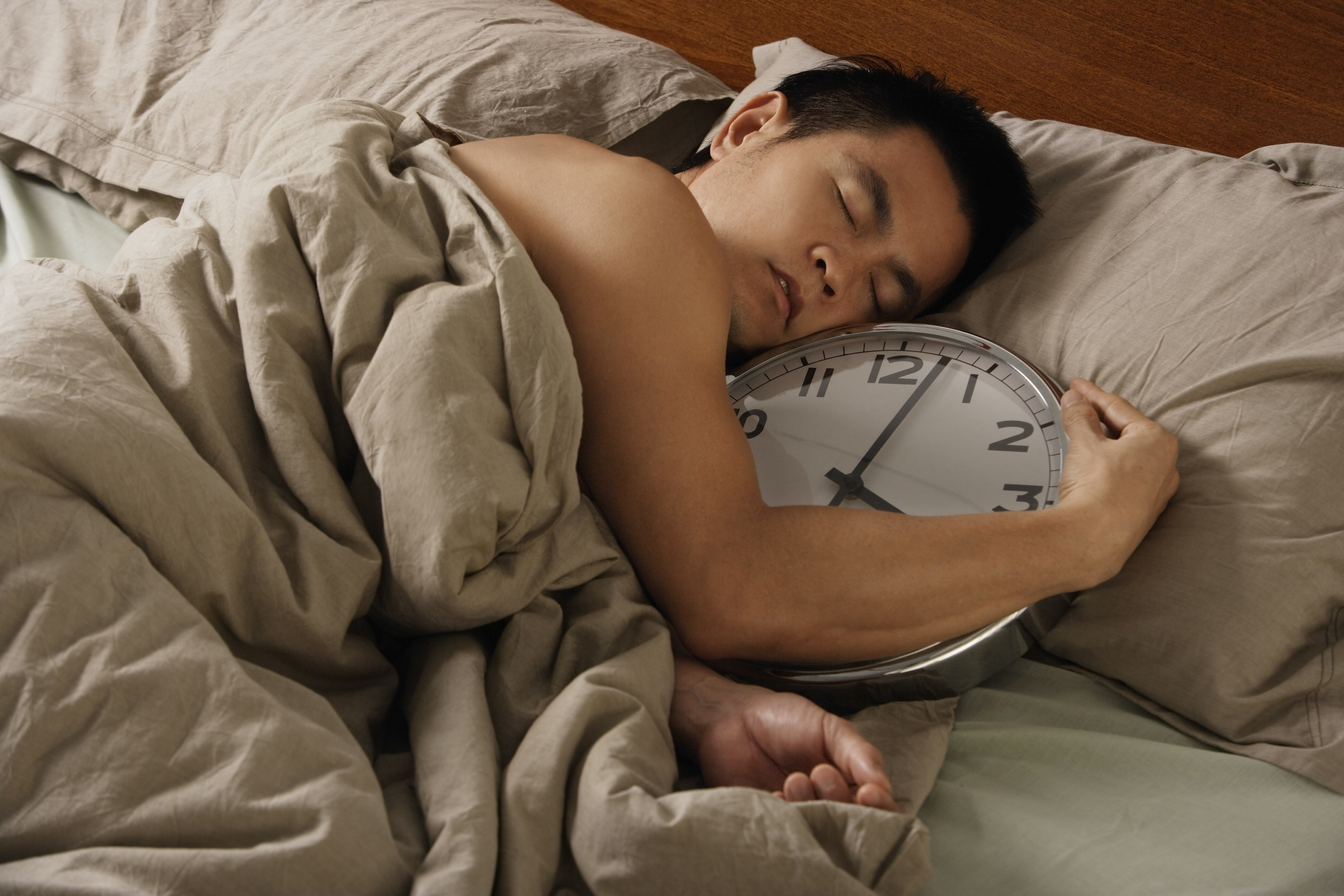 Man holding large clock in bed