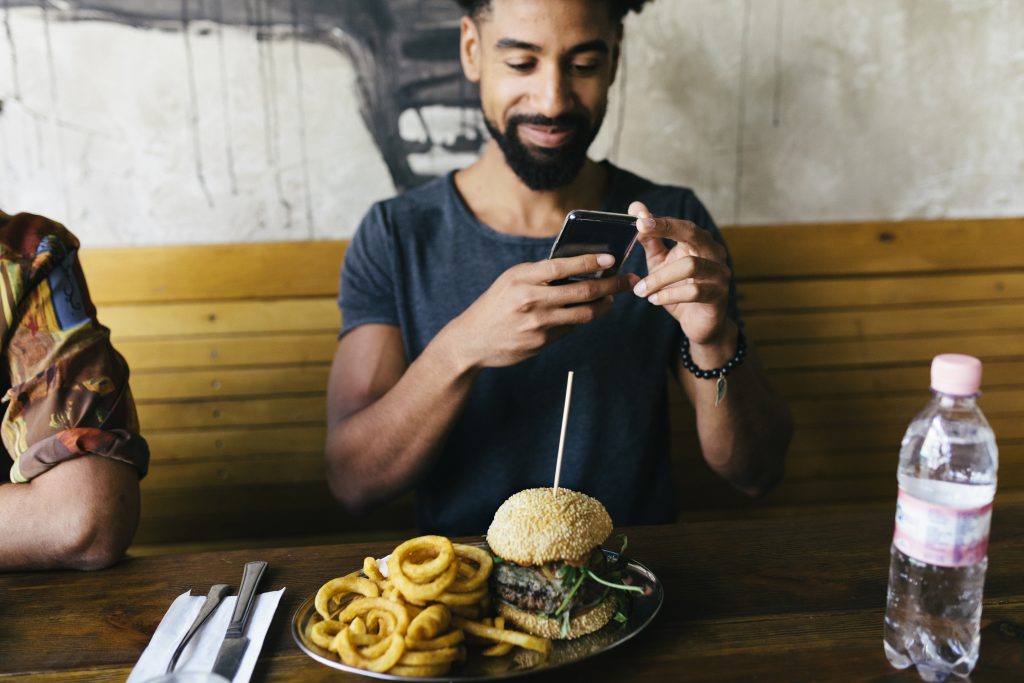 Man Taking Photos Of Burger With Smartphone