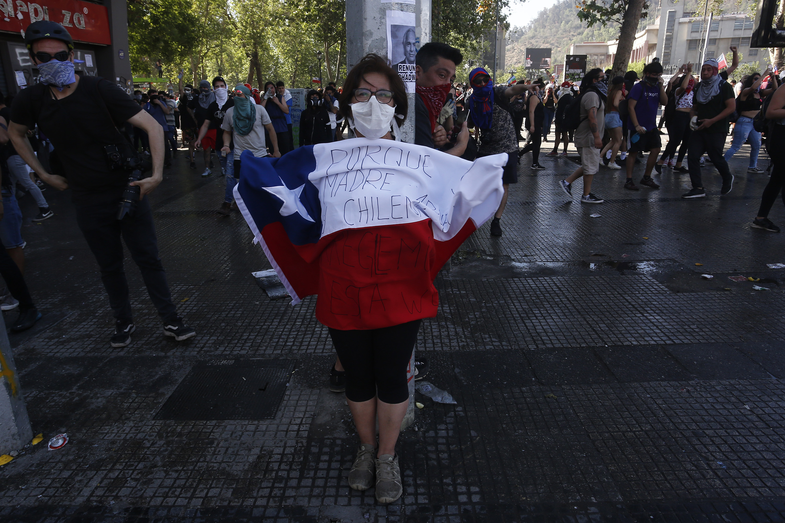 A woman with a comfort mask holds a Chilean flag during a protest in the capital city of Santiago