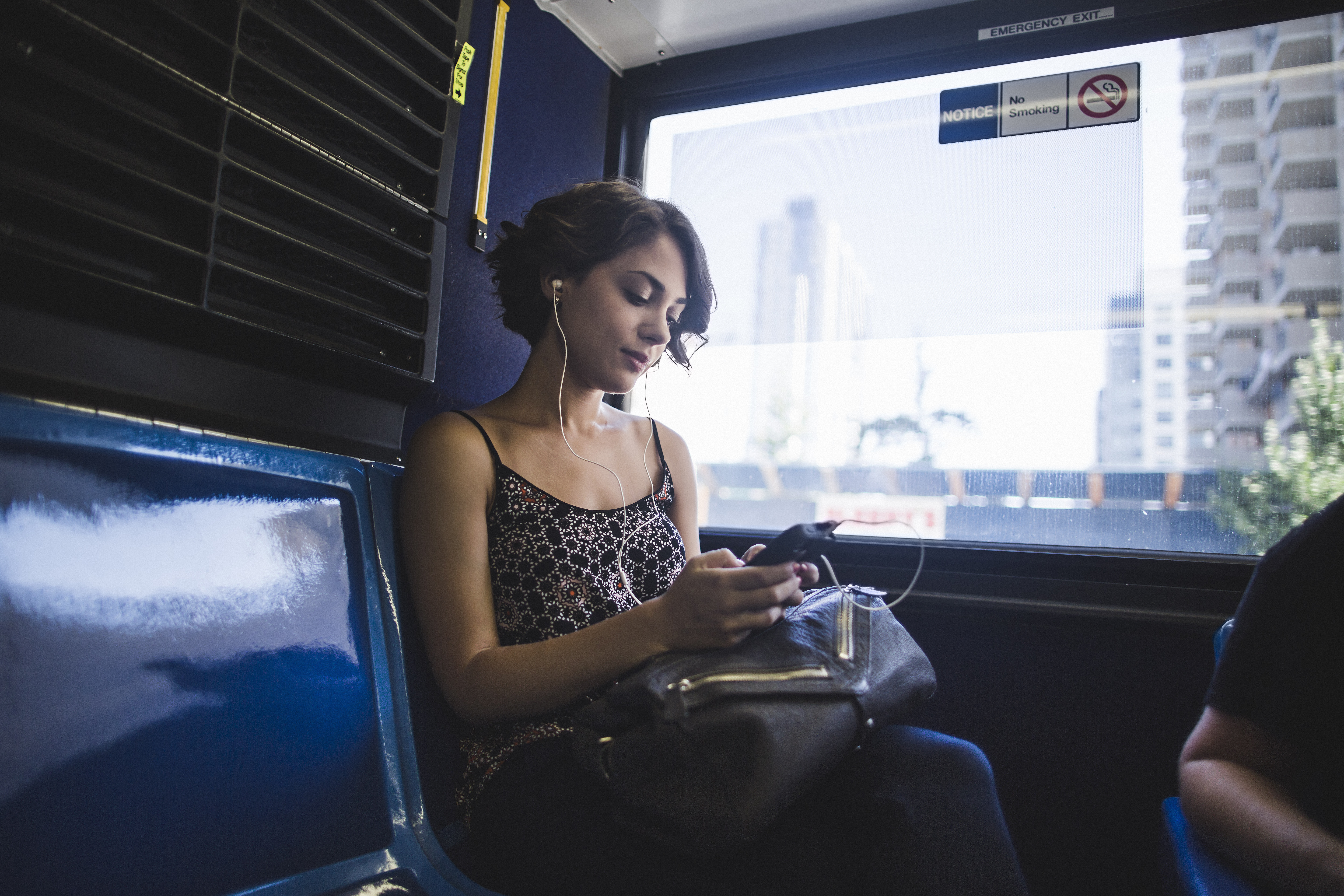 Young woman commuting on bus listening to music on smartphone. (Getty Images)