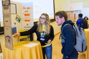 A young woman shows a student a display about artificial intellligence at an innovation event