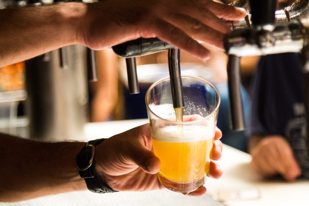 Closeup of hand pouring beer from draft.