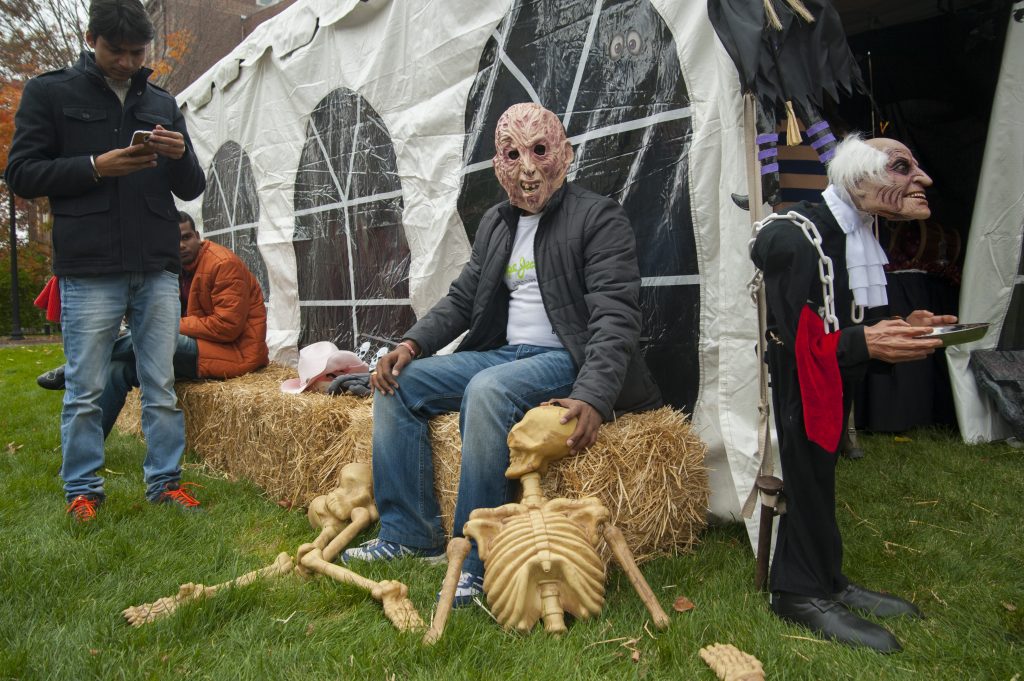 Students in scary Halloween masks gather outside a tent