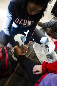 A student helps a homeless person try on some new shoes during the Footwear for Care event at UConn Hartford on Dec. 7, 2019. (Leonard Blanks/UConn Photo)