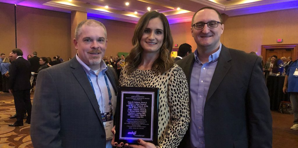 Kevin Chamberlin, Diana Sobieraj and William Baker at the ASHP Conference. Diana is holding a plaque for winning the 2019 Literary award