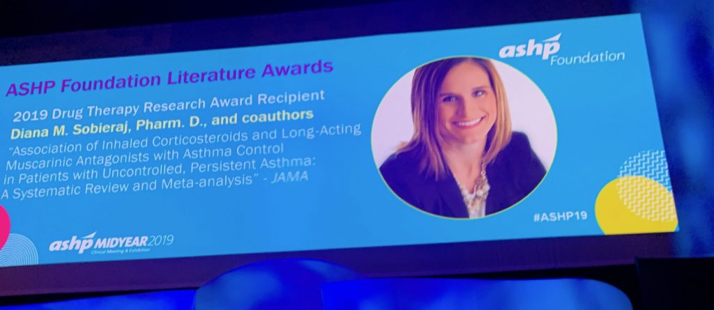 Announcement and photo on big screen at ASHP midyear event featuring Diana Sobieraj who received the 2019 ASHP Foundation Literature Award