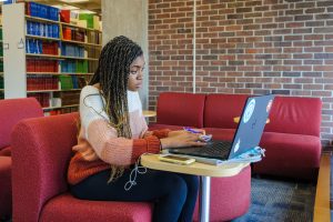 A young woman looking intently at the screen of a laptop computer while studying in the Homer Babbidge Library.