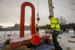 Workers attach cables to the sculpture to lift it out of the ground. (Sean Flynn/UConn Photo)