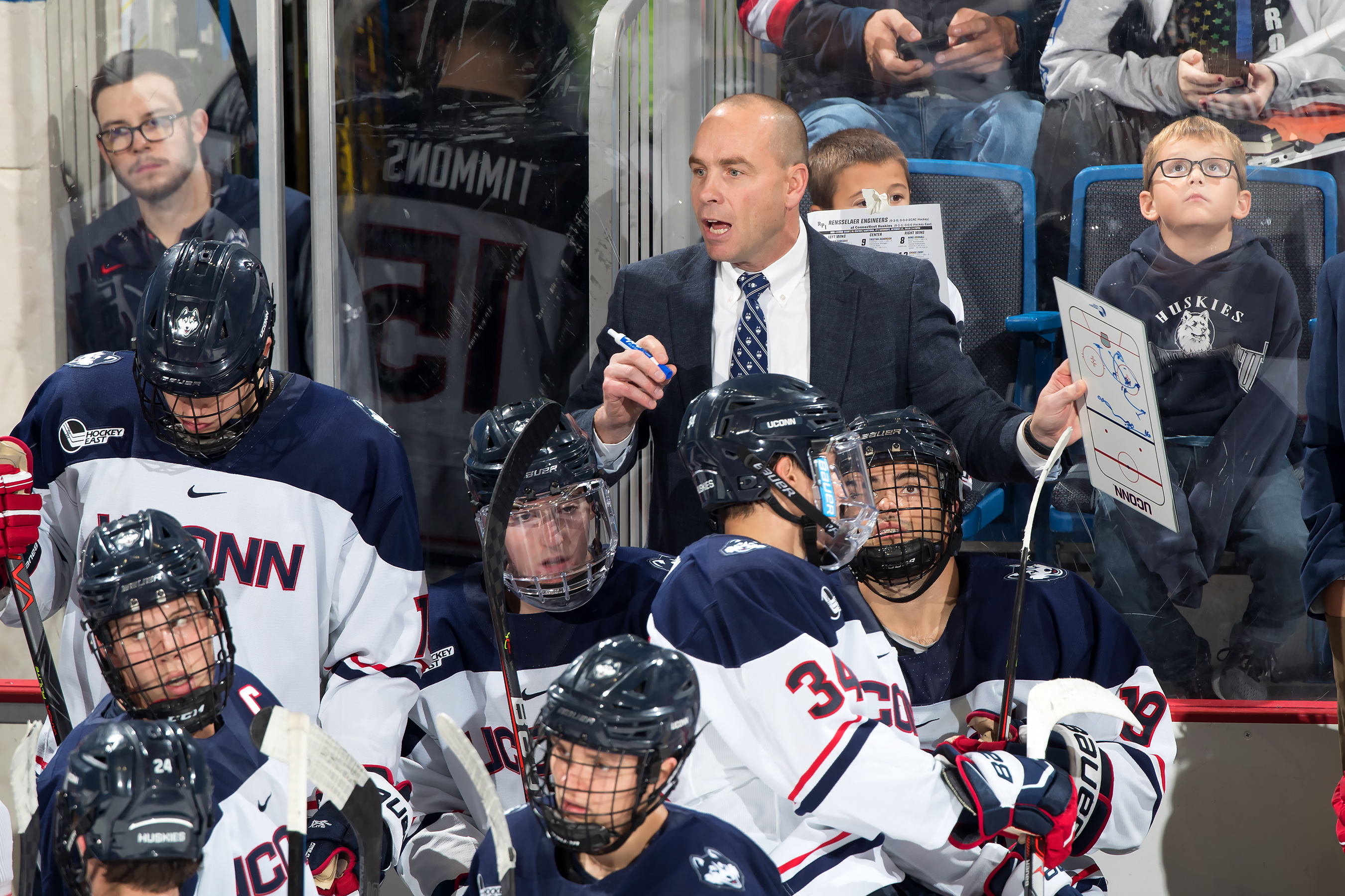 UConn men's ice hockey Coach Mike Cavanaugh on the bench during a game.