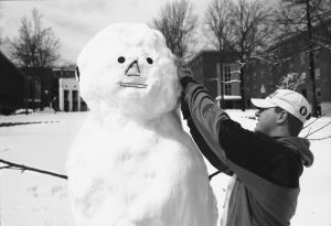 Freshman Mike Kapareiko puts the finishing touches on a snowman outside North Campus after a 1997 storm that dumped more than a foot of snow on Storrs. (Peter Morenus/UConn File Photo)