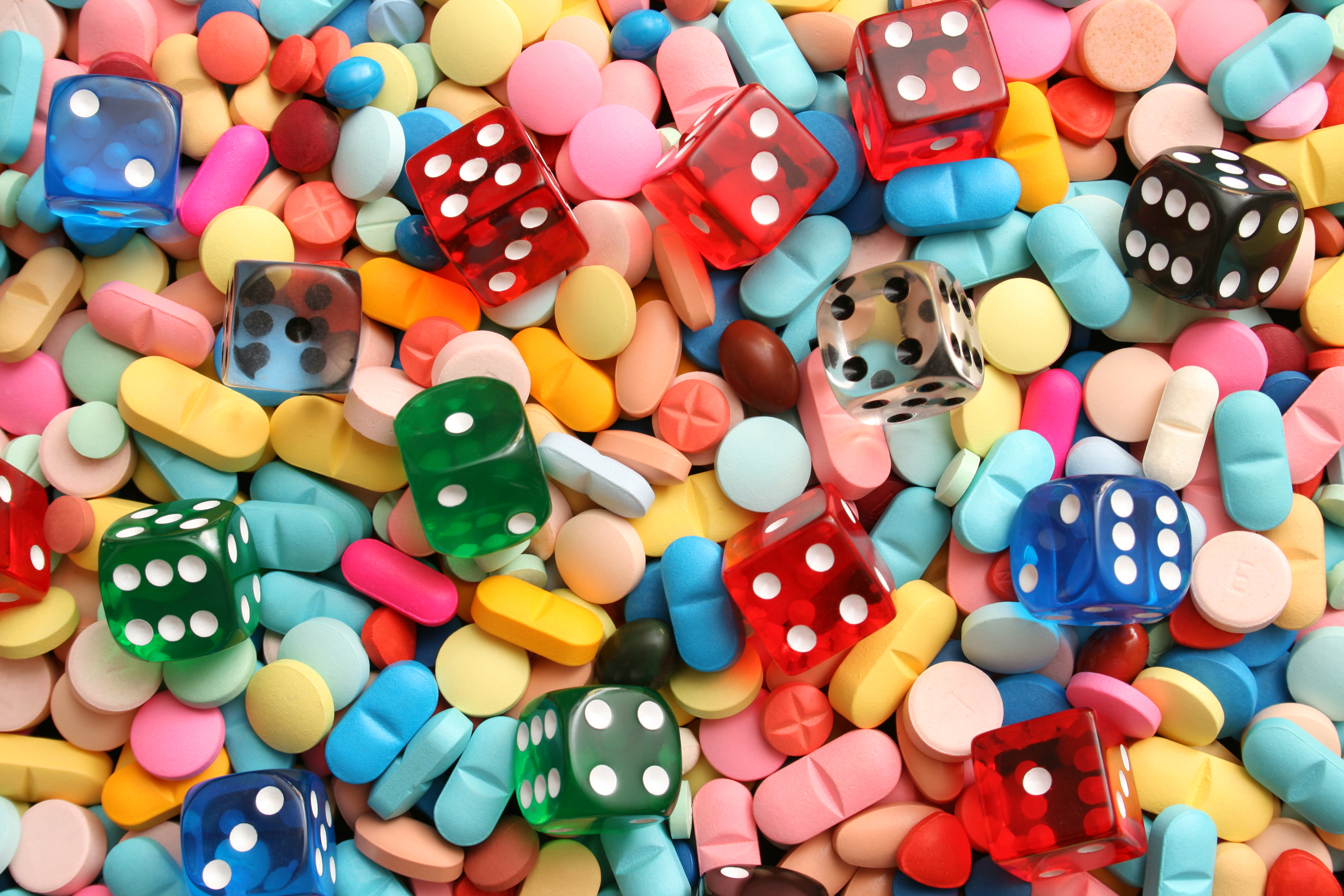 A multicolored array of pills, mixed in with dice to illustrate the risk of untested dietary supplements.