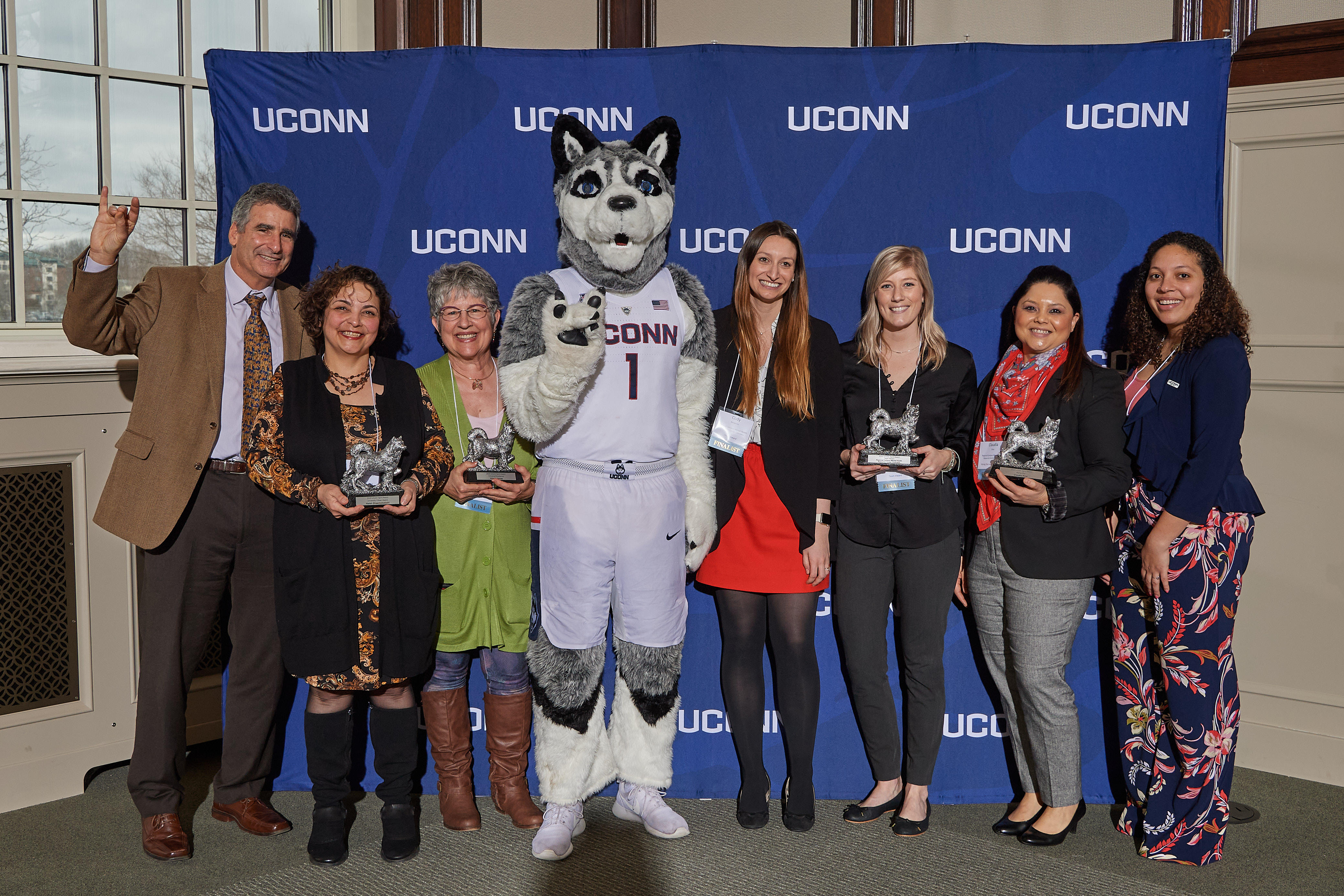 President Tom Katsouleas and Jonathan the Husky pose with 2020 UConn Spirit awards recipients at the Wilbur Cross North Reading Room