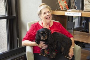 Dr. Karen Obadowski with her Cavalier King Charles spaniel on her lap in the Health Sciences Library