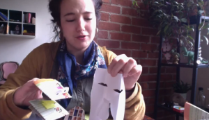 MFA student Felicia Cooper, a graduate assistant at the Ballard Institute and Museum of Puppetry, shows the paper puppet and mask she made during an online video that can be found at the Ballard website. (Photo courtesy Ballard Institute and Museum of Puppetry)