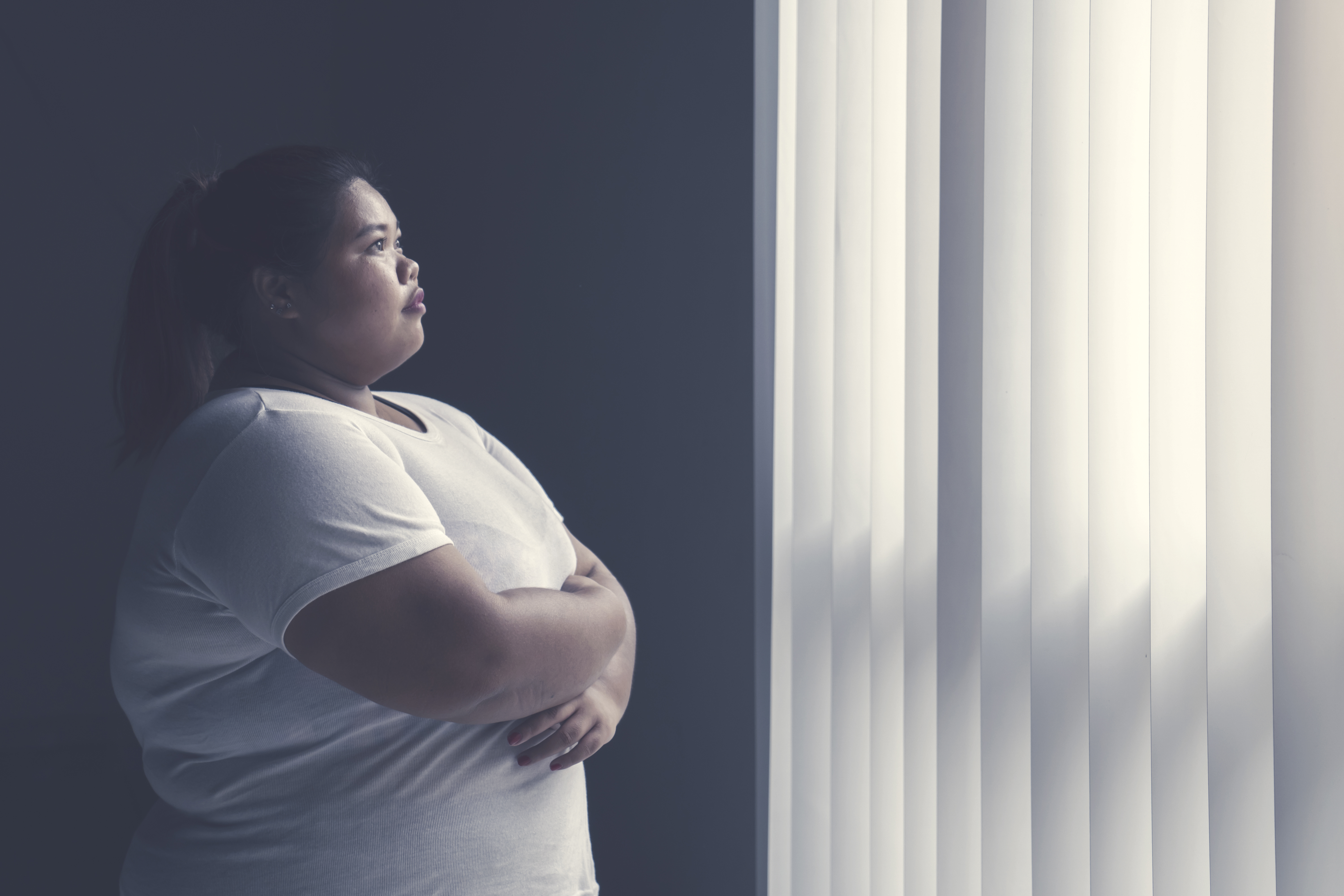 An overweight woman looks out a window