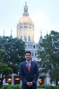 Michael Hernandez, UConn's fifth Newman Civic Fellow, poses in front of the state Capitol in Hartford.