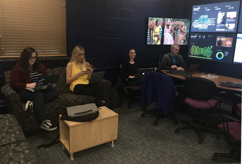 Students and faculty members sit before the multi-screen bank of the Social Media Analytics Command Center at UConn.