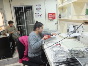 Bree Mora using a heat gun to shrink protective tubing around a connection. (Photo by Christina Baer)