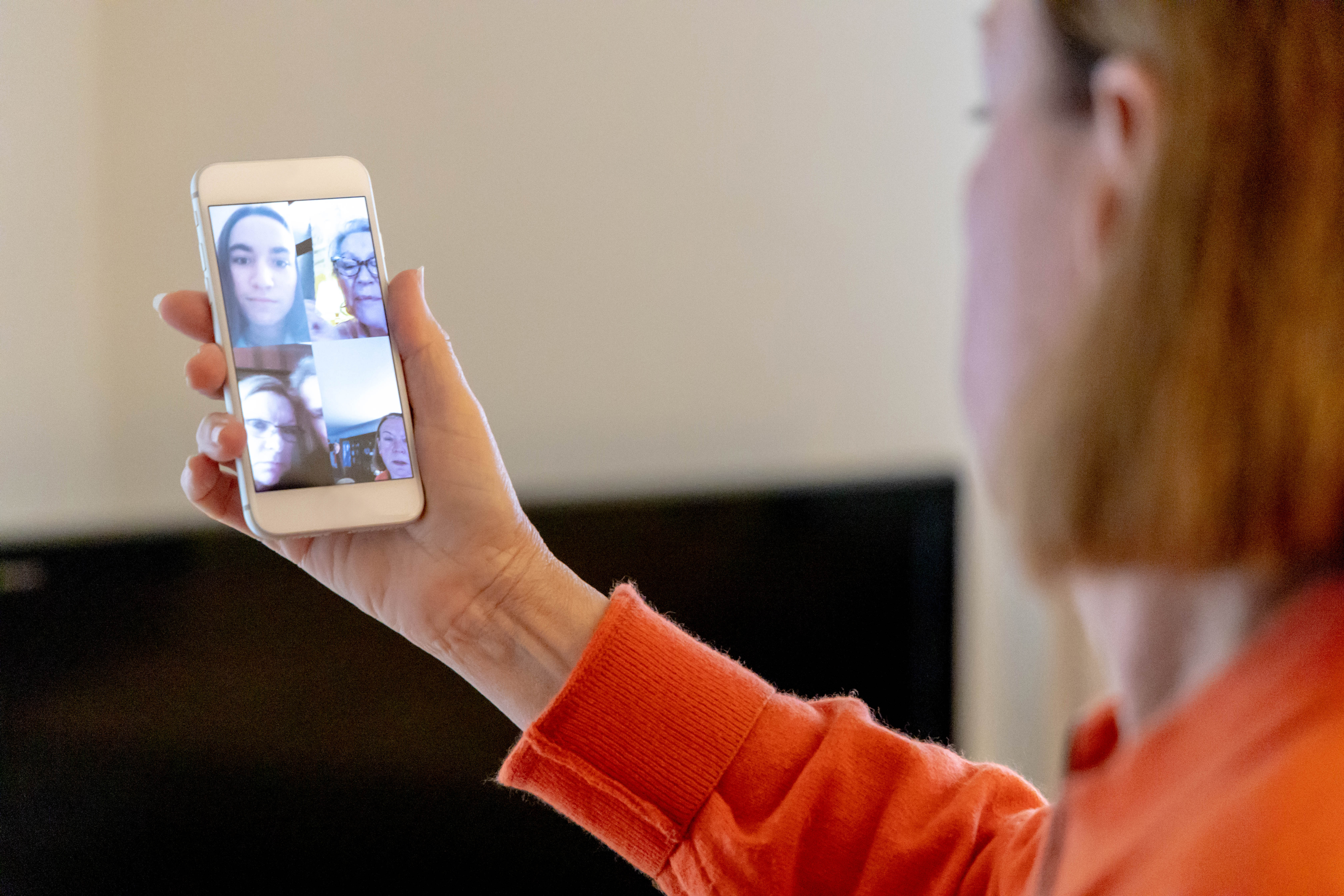 An older woman has a video chat on her phone with a younger woman.