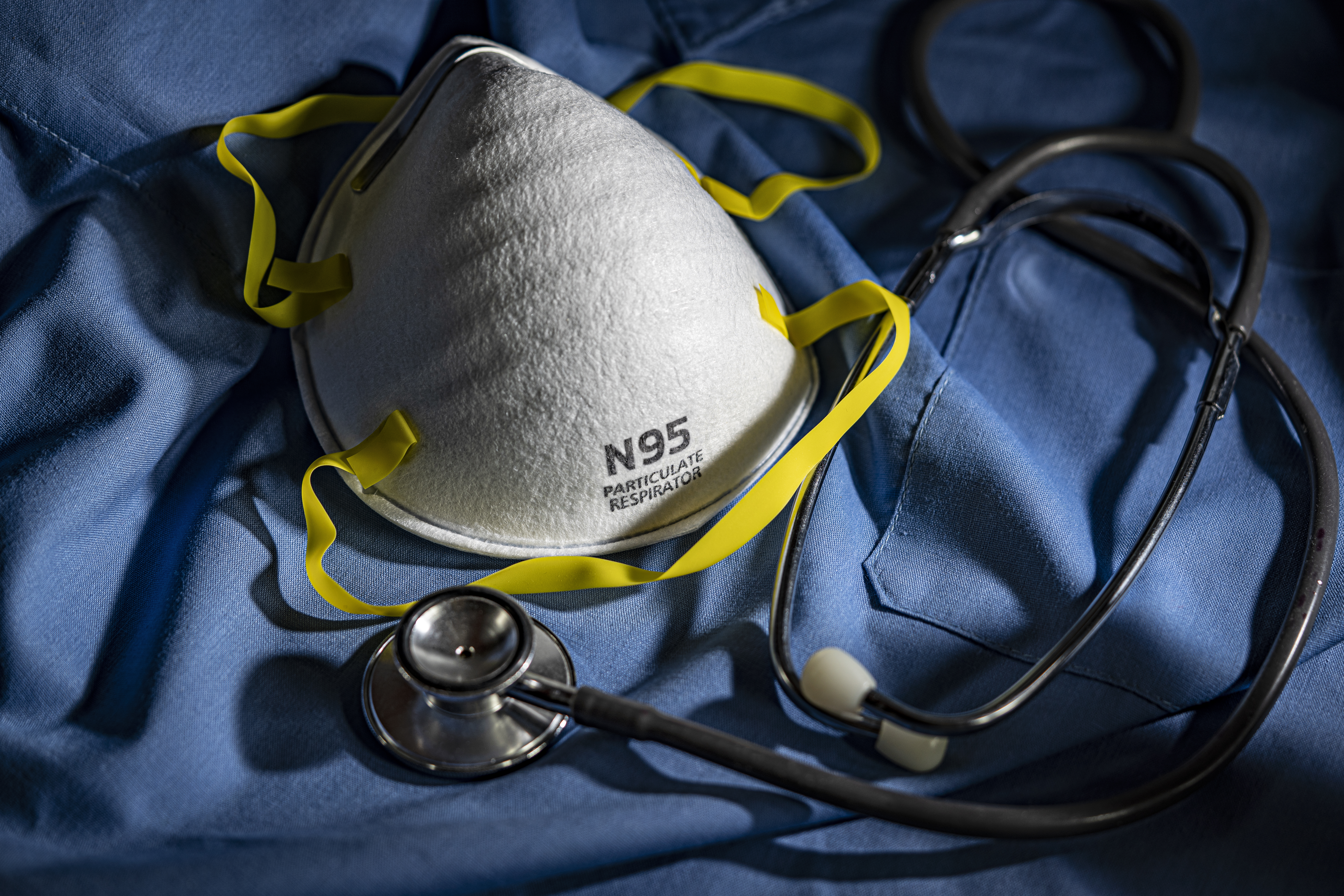 Close-up of Protective N95 Mask on Blue Scrubs with Stethoscope