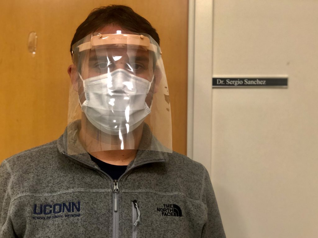 Dr. Sergio Sanchez Velasco models a face shield made through the 3D printing process to help protect dental residents and other health care workers from exposure to the novel coronavirus. (UConn Health Photo)