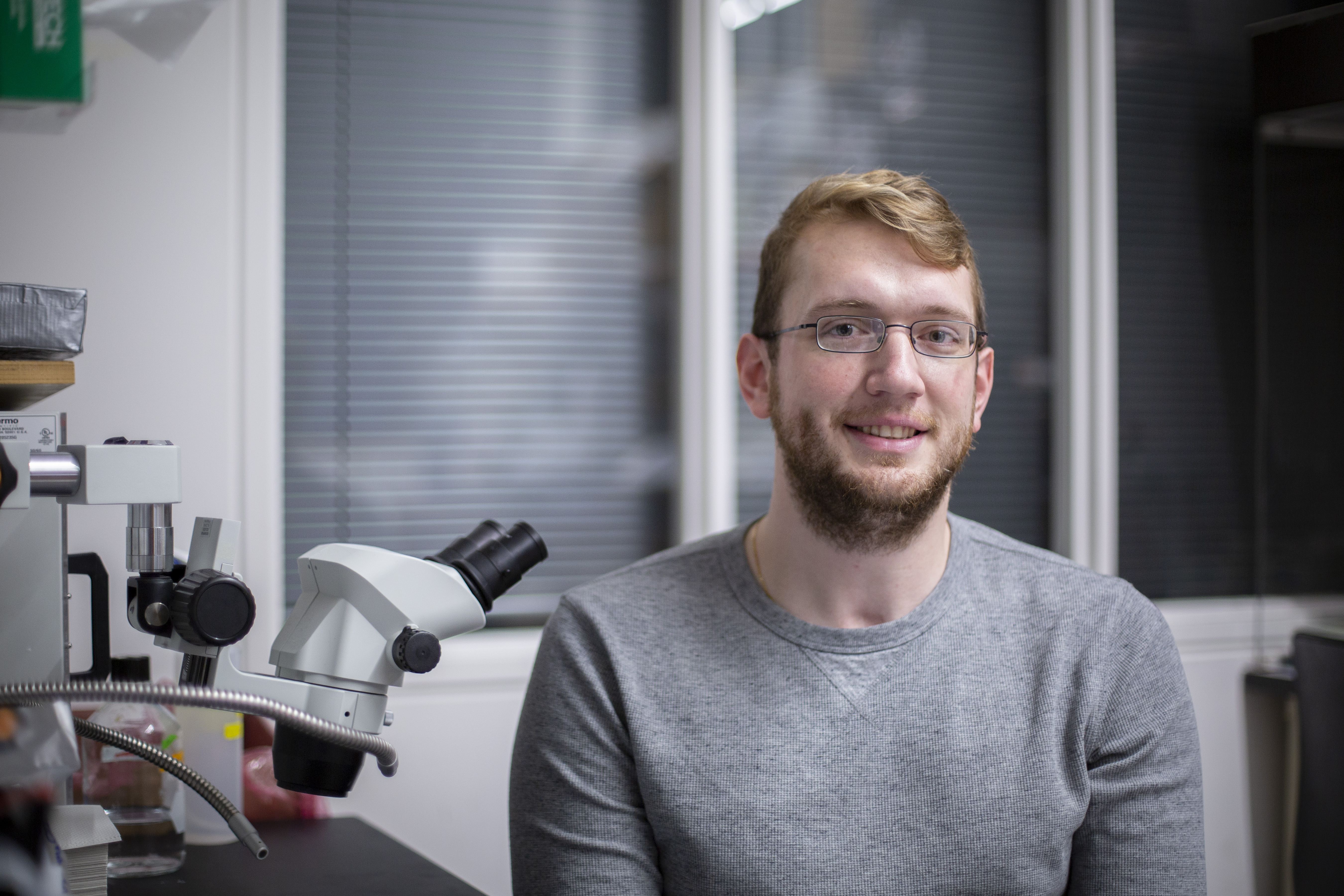 Jeff Rasumussen '20 (CLAS) sits by a microscope in his PNB lab.