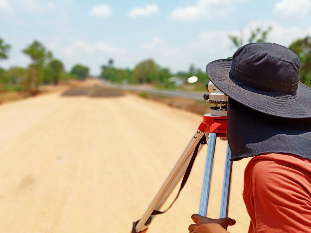 Female surveyor on dirt road.