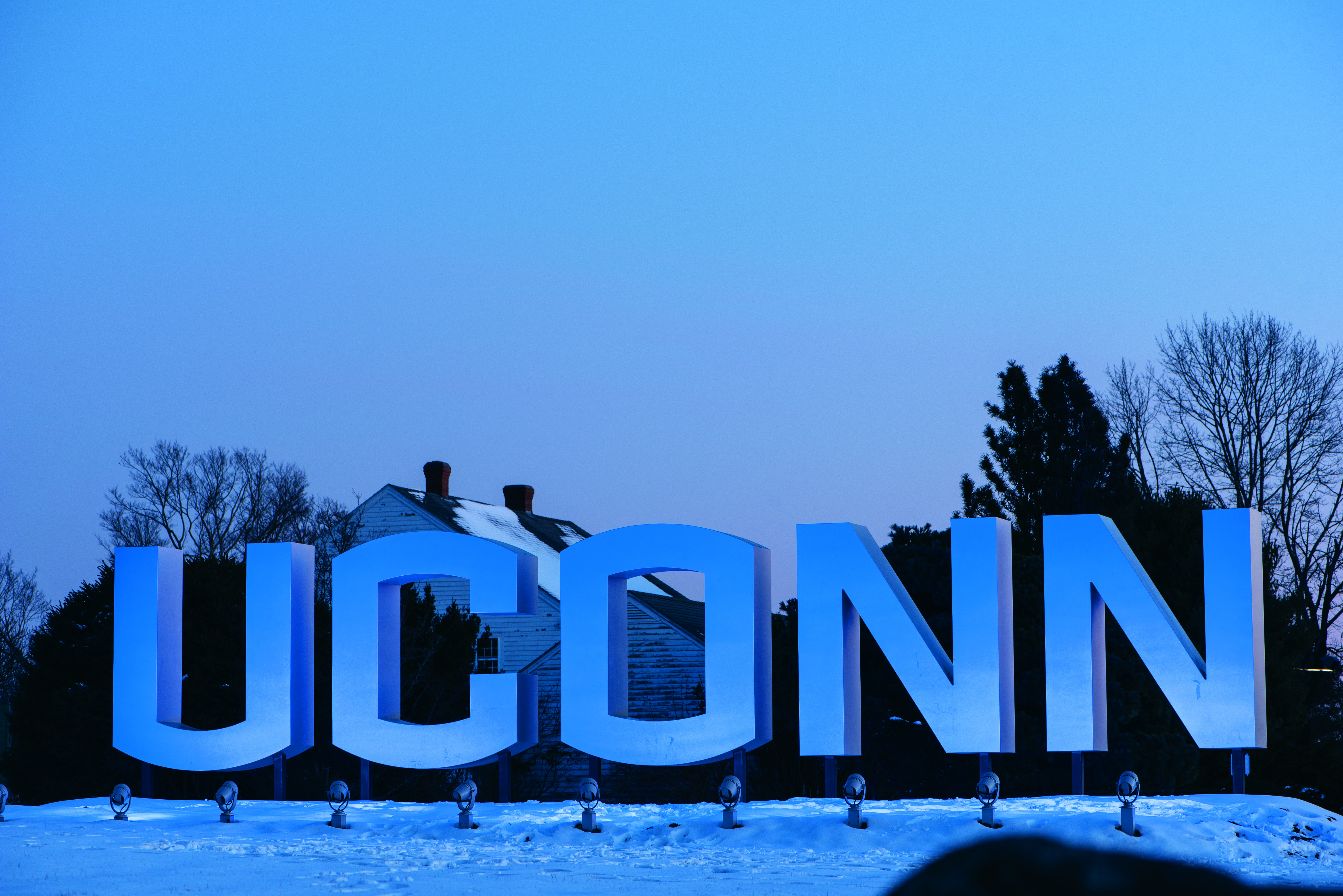 Blue lights casting across the large UConn branded sign at night during the winter on Jan. 22, 2020. (Sean Flynn/UConn Photo)