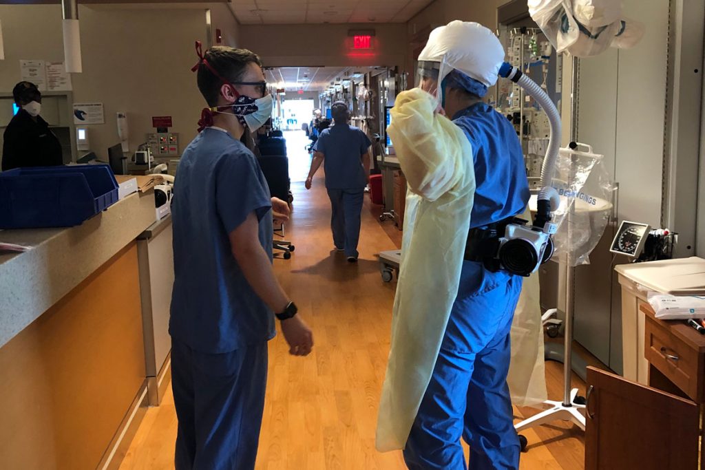 Health care providers in personal protective equipment on busy hospital floor