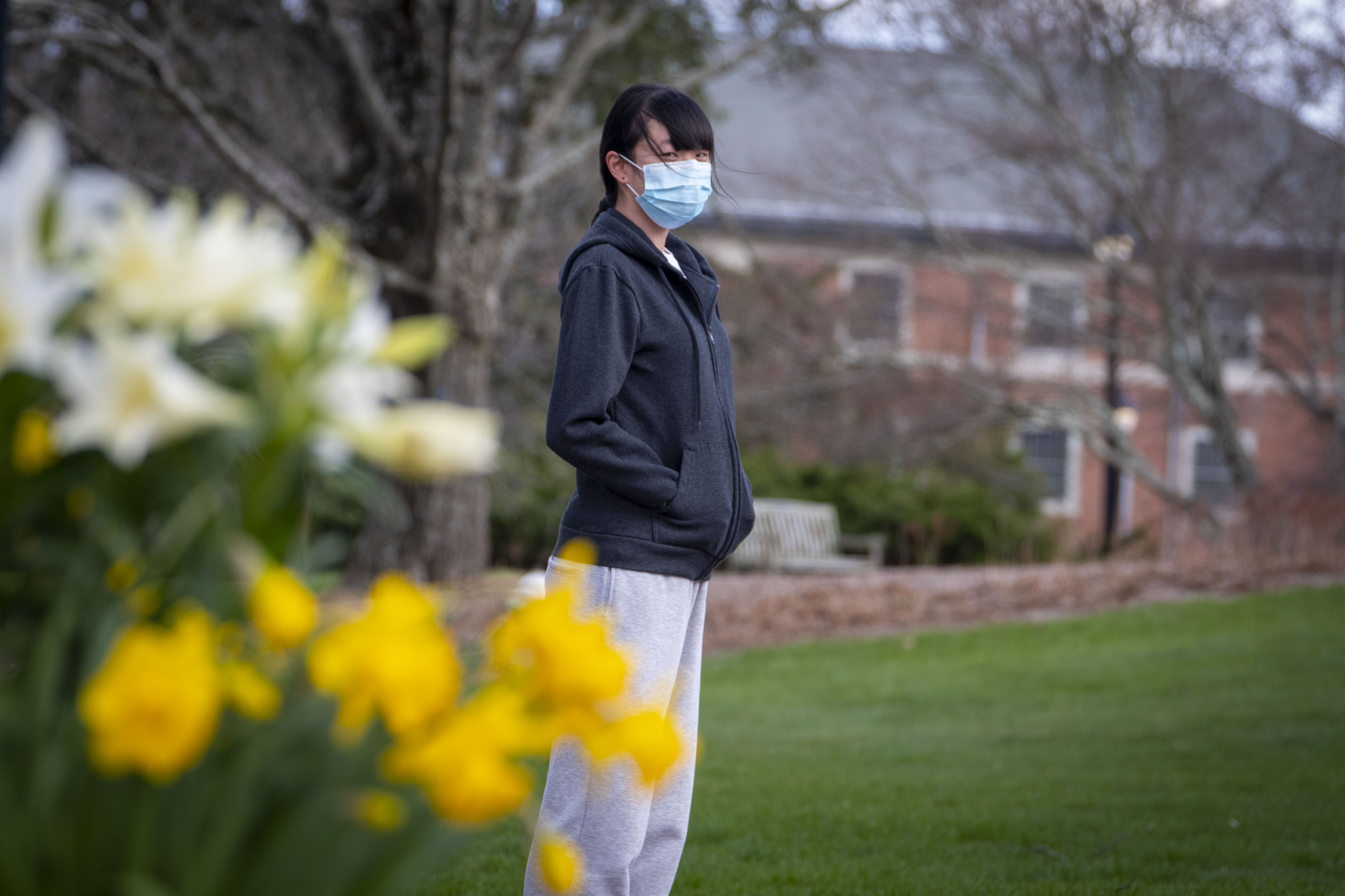 A student in a face mask stands in a mostly deserted part of campus during the COVID-19 pandemic.