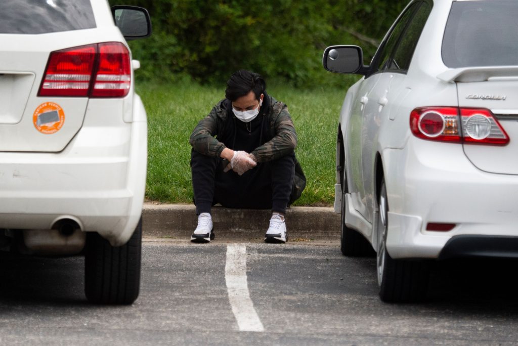 A mourner from the Nepali community, unable to attend the funeral for Ashish KC due to social distancing restrictions, reacts in the parking lot outside of the Maryland Cremation services in Millersville, Maryland on May 20, 2020. - Ashish died in a drowning but due to restrictions in place amid the novel coronavirus pandemic, only eight close family members and friends were allowed to attend the ceremony inside, while more then 30 waited outside. Mourners inside live streamed the funeral to family back in Nepal and to those waiting just outside. The coronavirus pandemic has drastically altered the way we are able to mourn and say goodbye to loved ones. (Photo by ANDREW CABALLERO-REYNOLDS / AFP) (Photo by ANDREW CABALLERO-REYNOLDS/AFP via Getty Images)