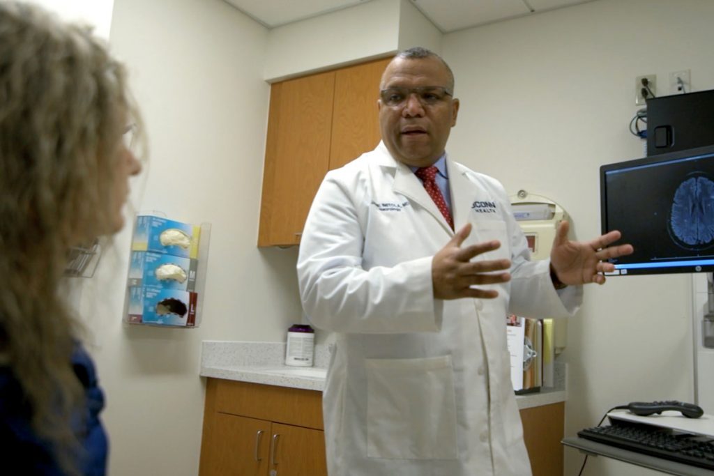 Dr. Imitola speaking to patient in exam room