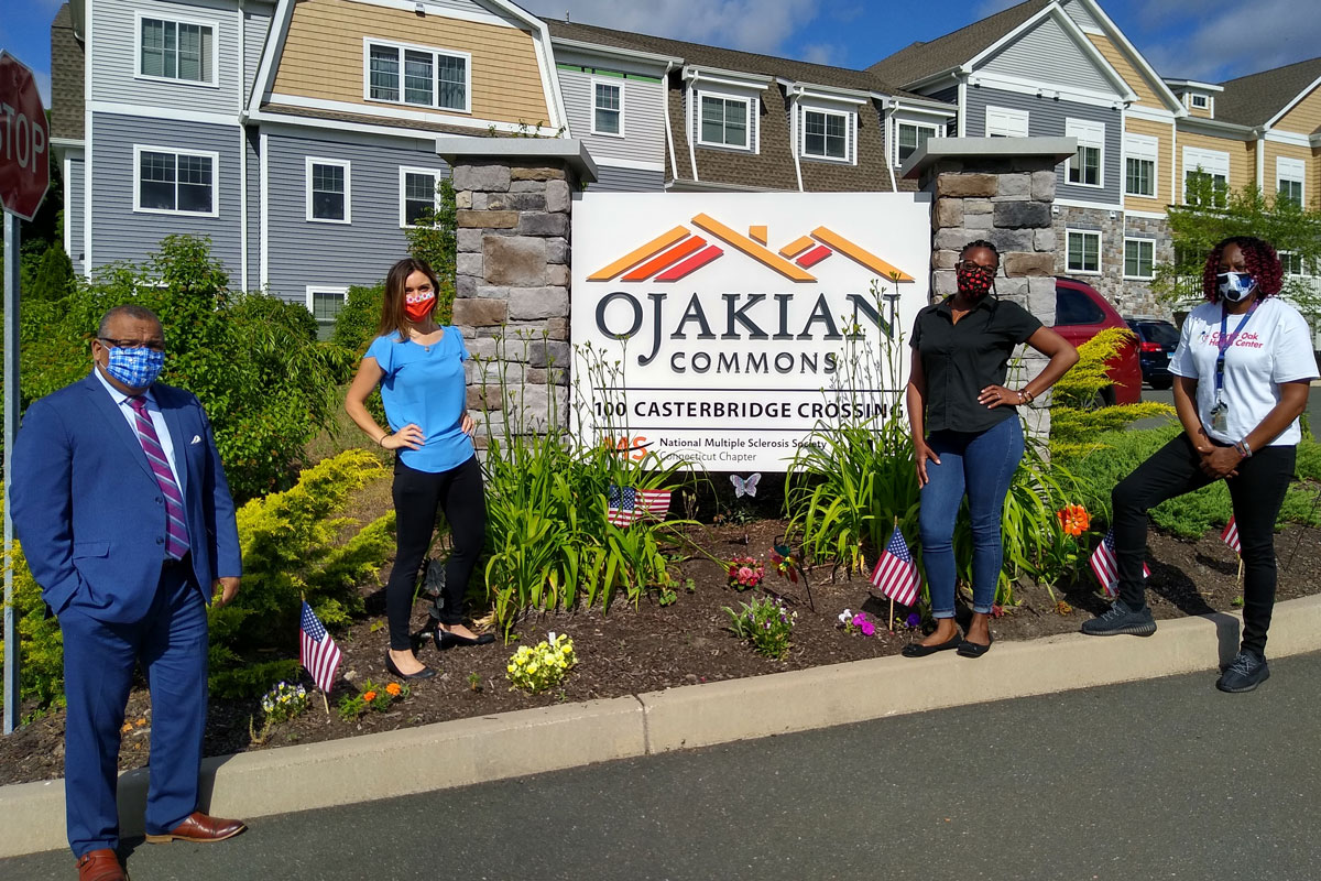 Group portrait (wearing masks) by the sign for Ojakian Commons