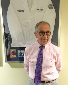 Dr. Beebe in front of a framed white coat