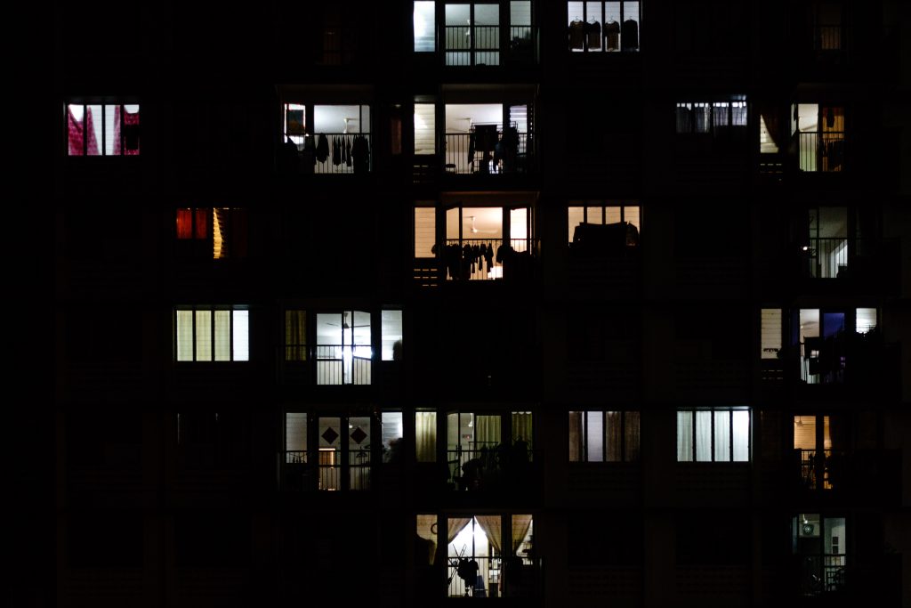 An apartment building at night, with some of the windows illuminated.