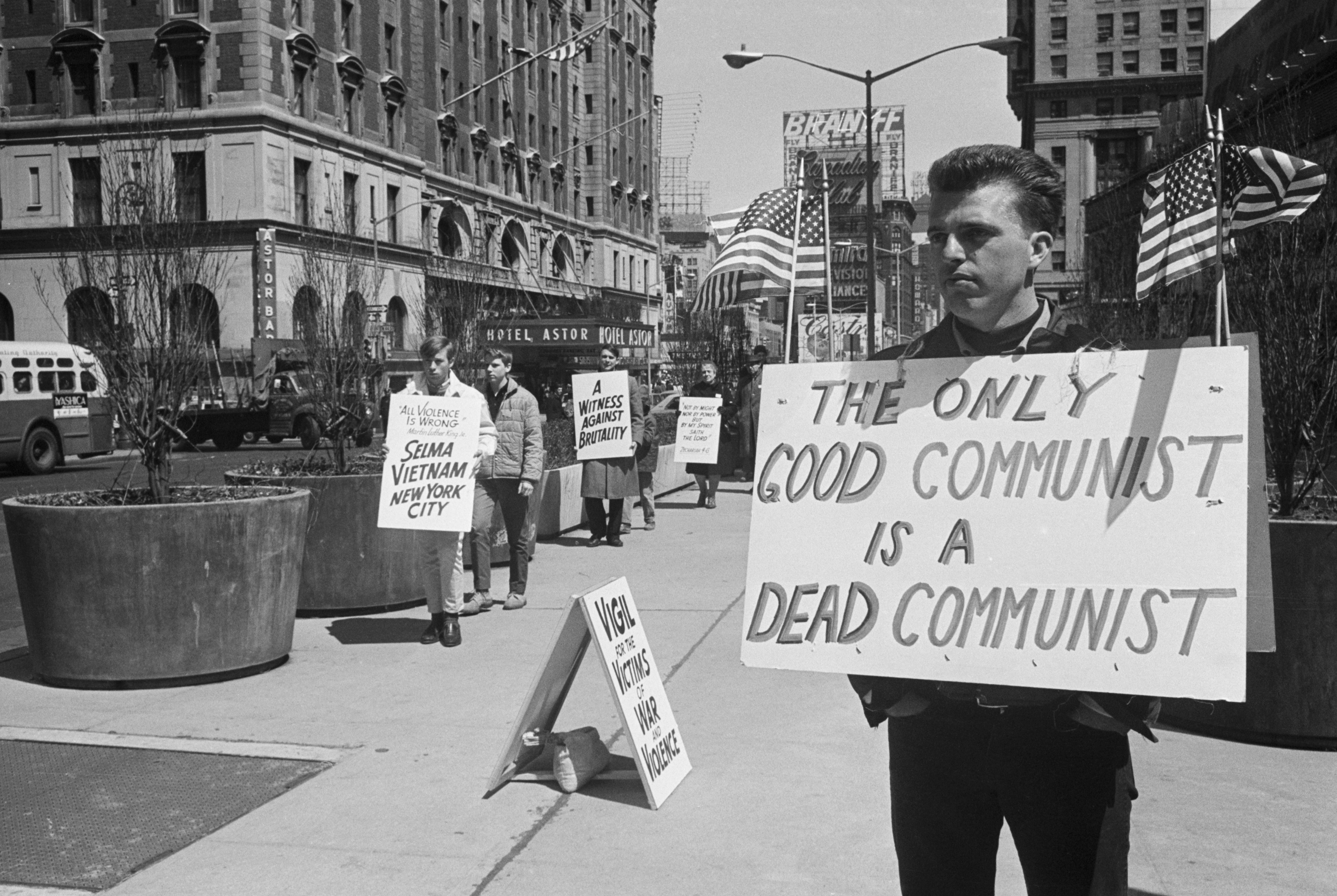 Antiwar protesters in 1965 stand to the left of a counter-demonstrator with a sign reading "The Only Good Communist is a Dead Communist."