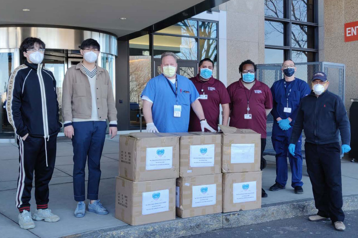 Representatives of groups that donated and UConn Health staff/vendors with six boxes of personal protective equipment in front of the UConn Health main entrance