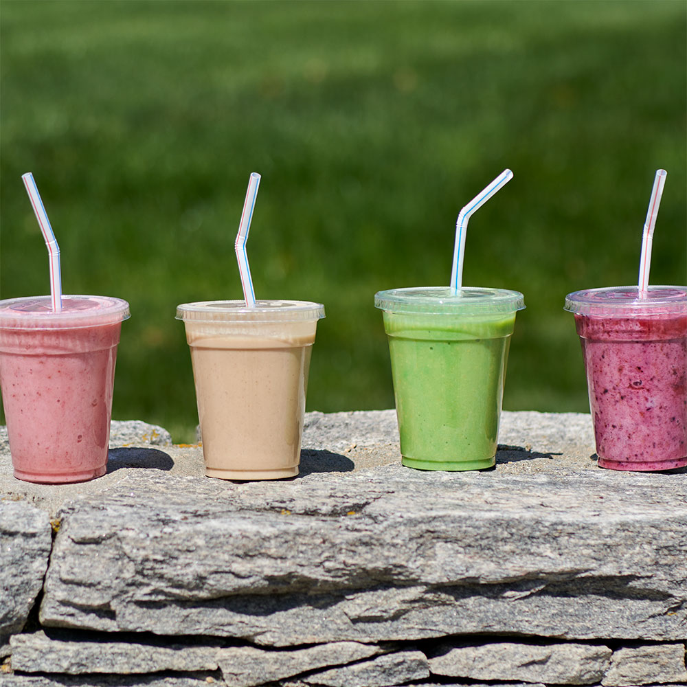 Four smoothies sitting on a rock wall.