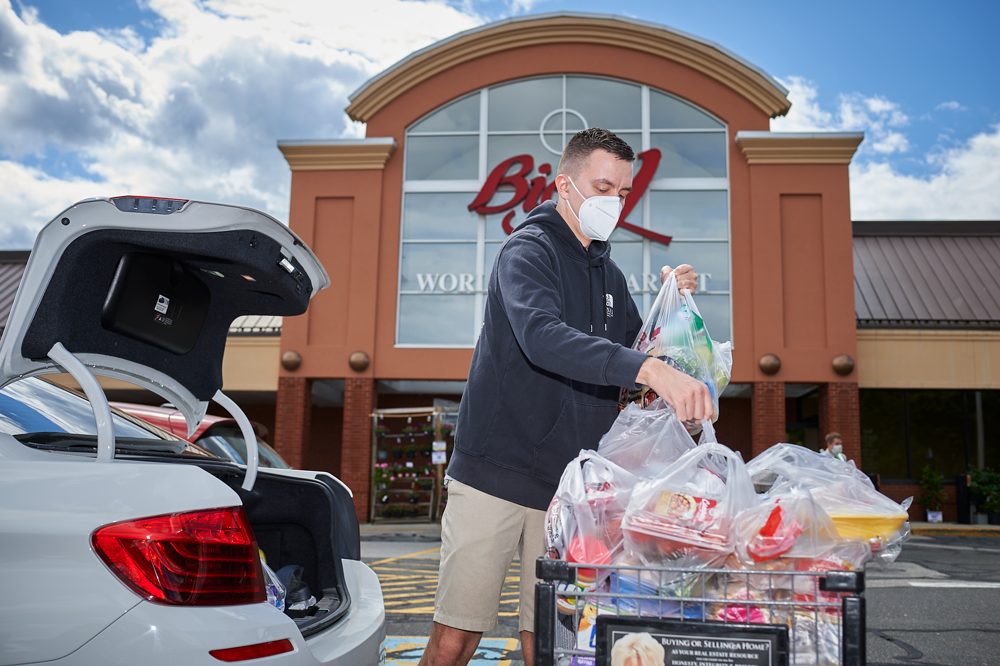 UConn alumn putting bags of groceries into car trunk.