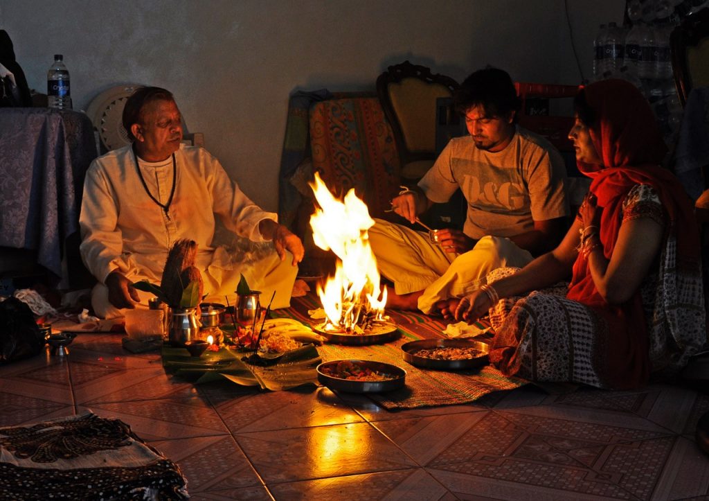 A family gathers around a traditional meal, with an open flame in the middle of the meal.