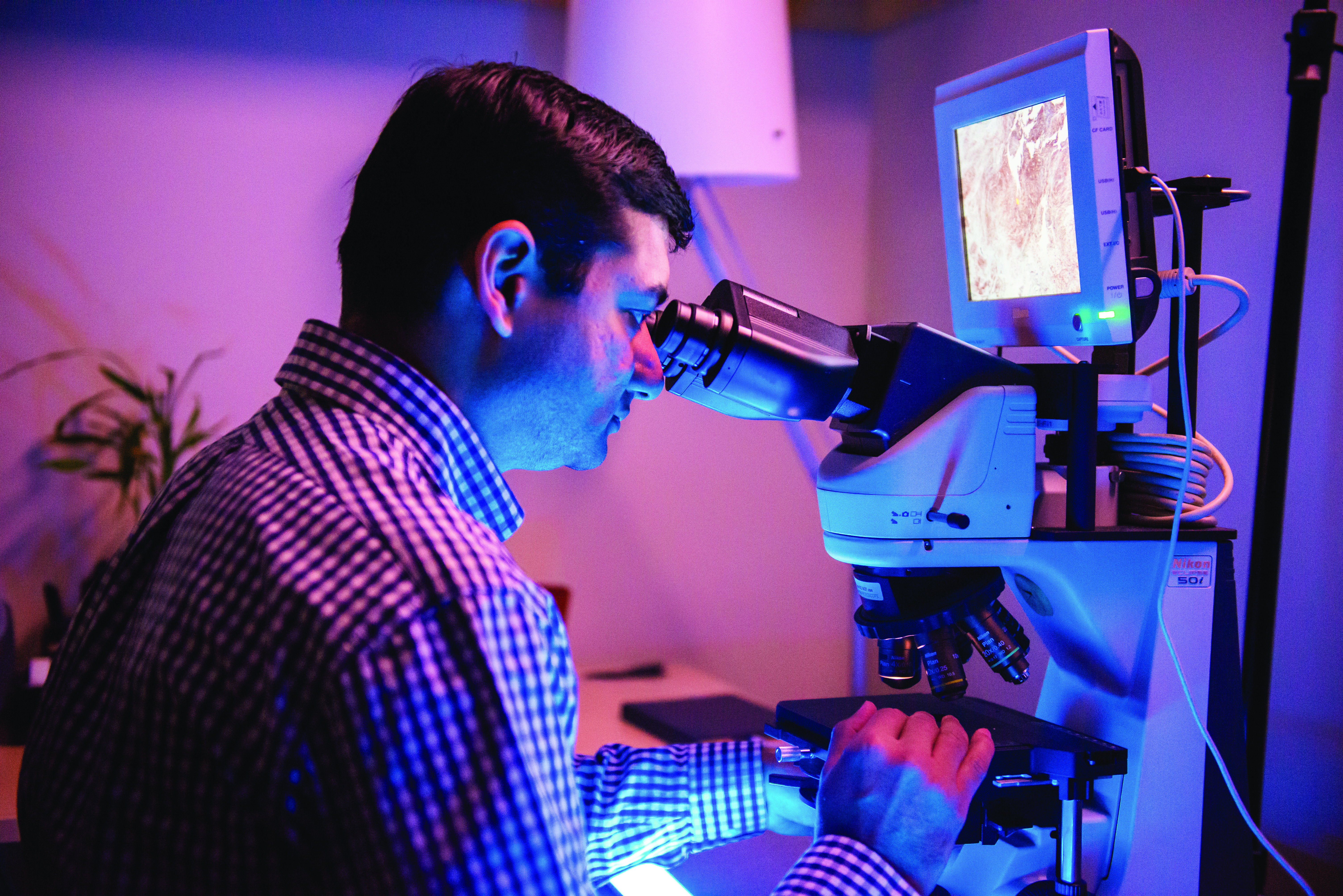UConn School of Dental Medicine oral pathologist Easwar Natarajan, BDS, D.M.Sc., examines a sample under a microscope.