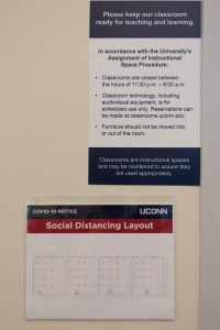 Two signs in a classroom with new social guidelines.