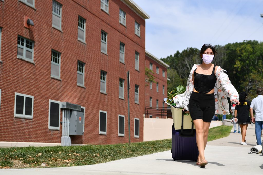 A student with a face covering moving into her dorm room at UConn