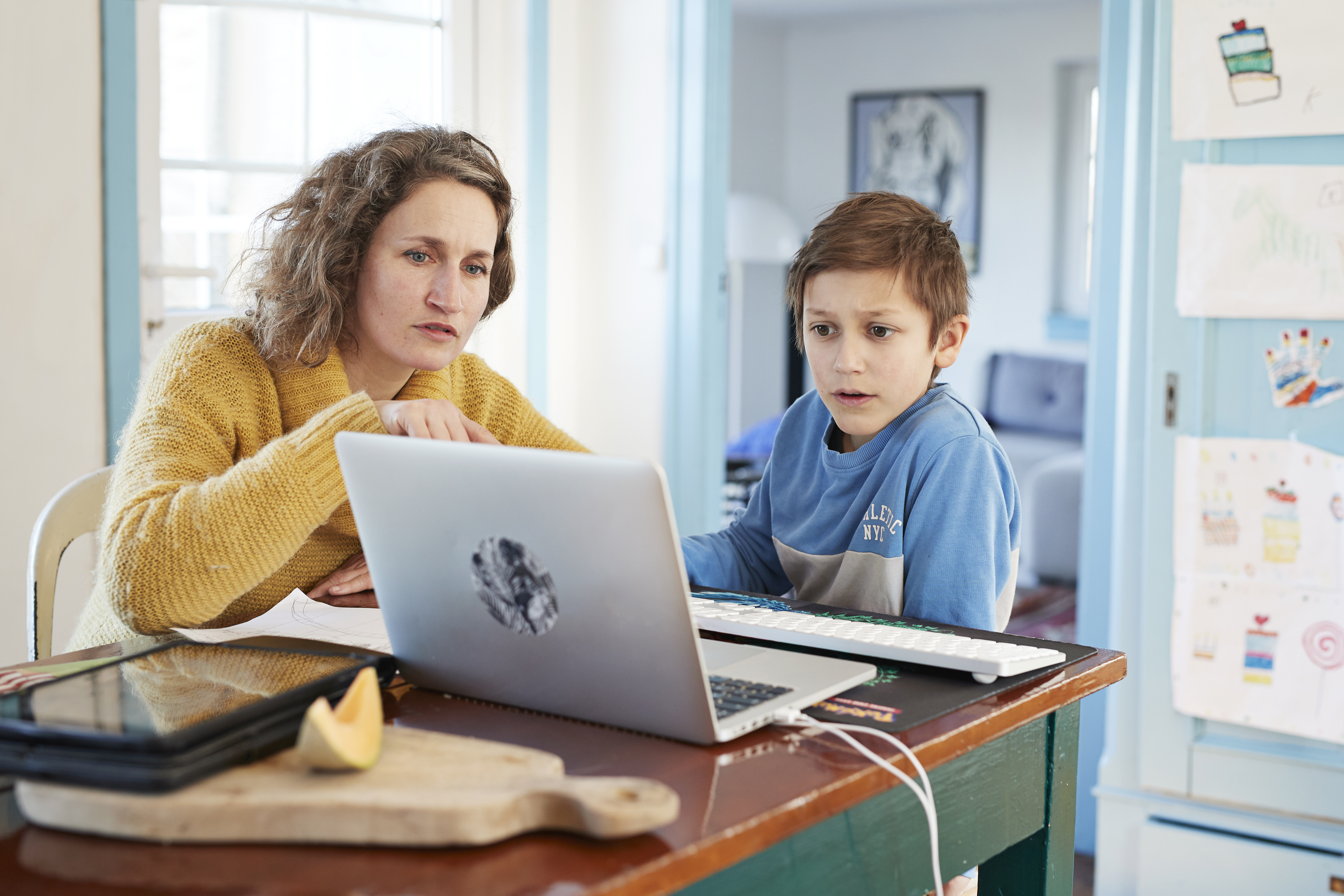 A mother helps her son with school work on a laptop computer.