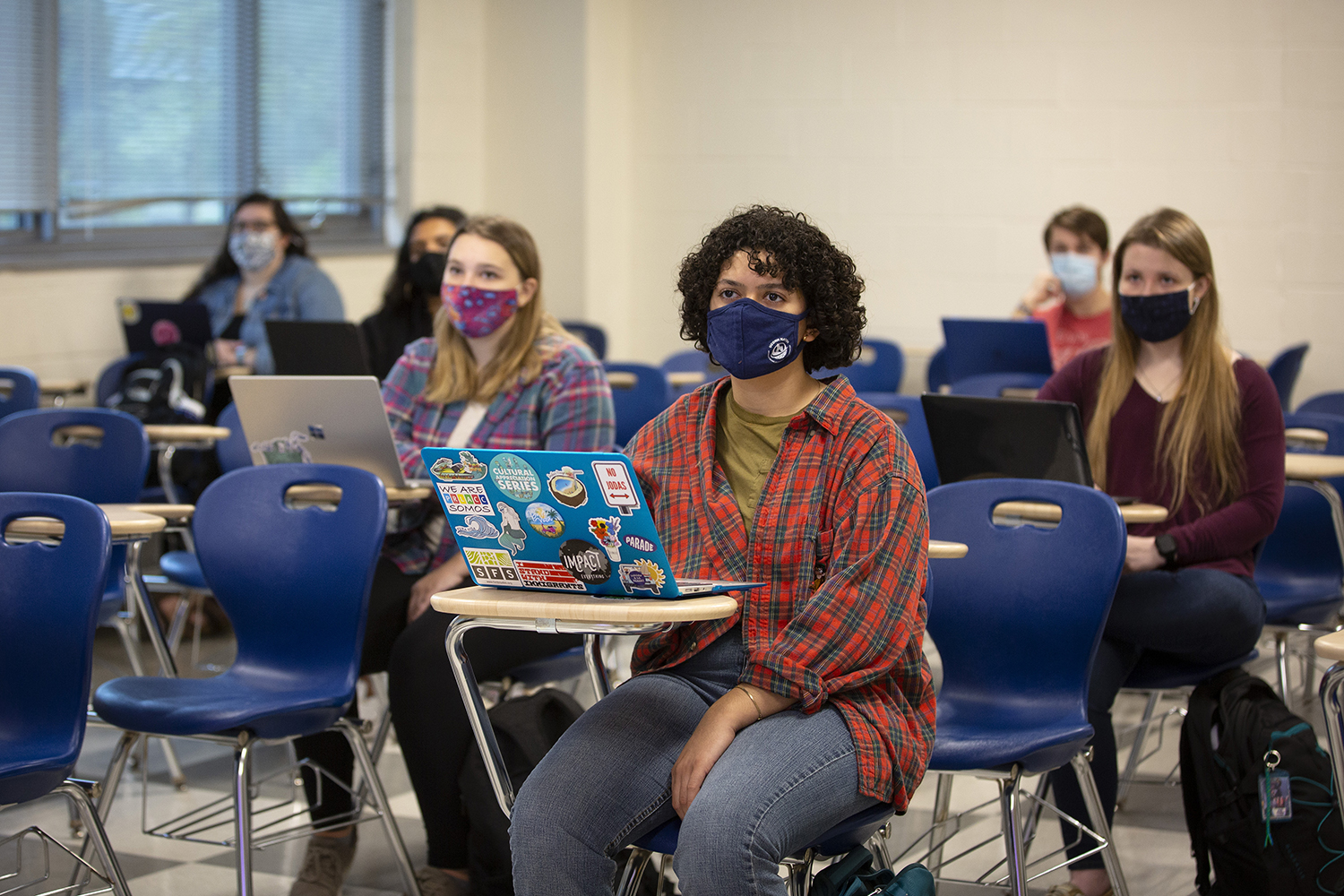 Students wearing face coverings listen to a lecture in a classroom.
