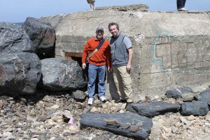 Associate Professor David Moss, right, and Professor Alan Marcus stand in front of a WWII German bunker on the beaches of Normandy in 2011. 