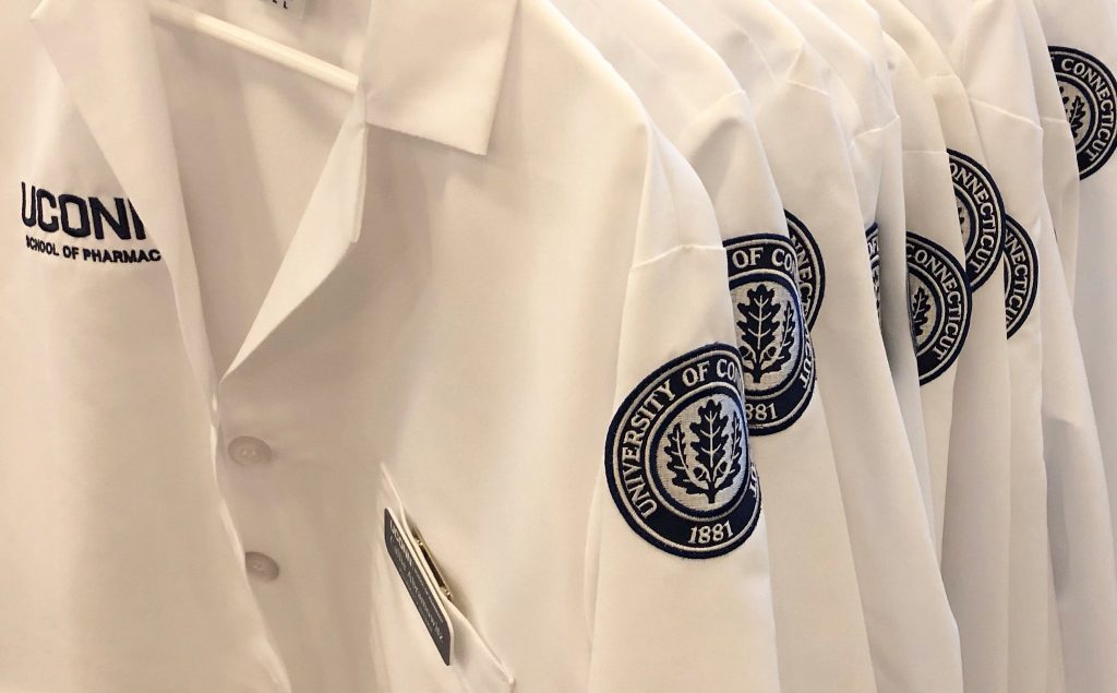 UConn School of Pharmacy white coats with logos close up