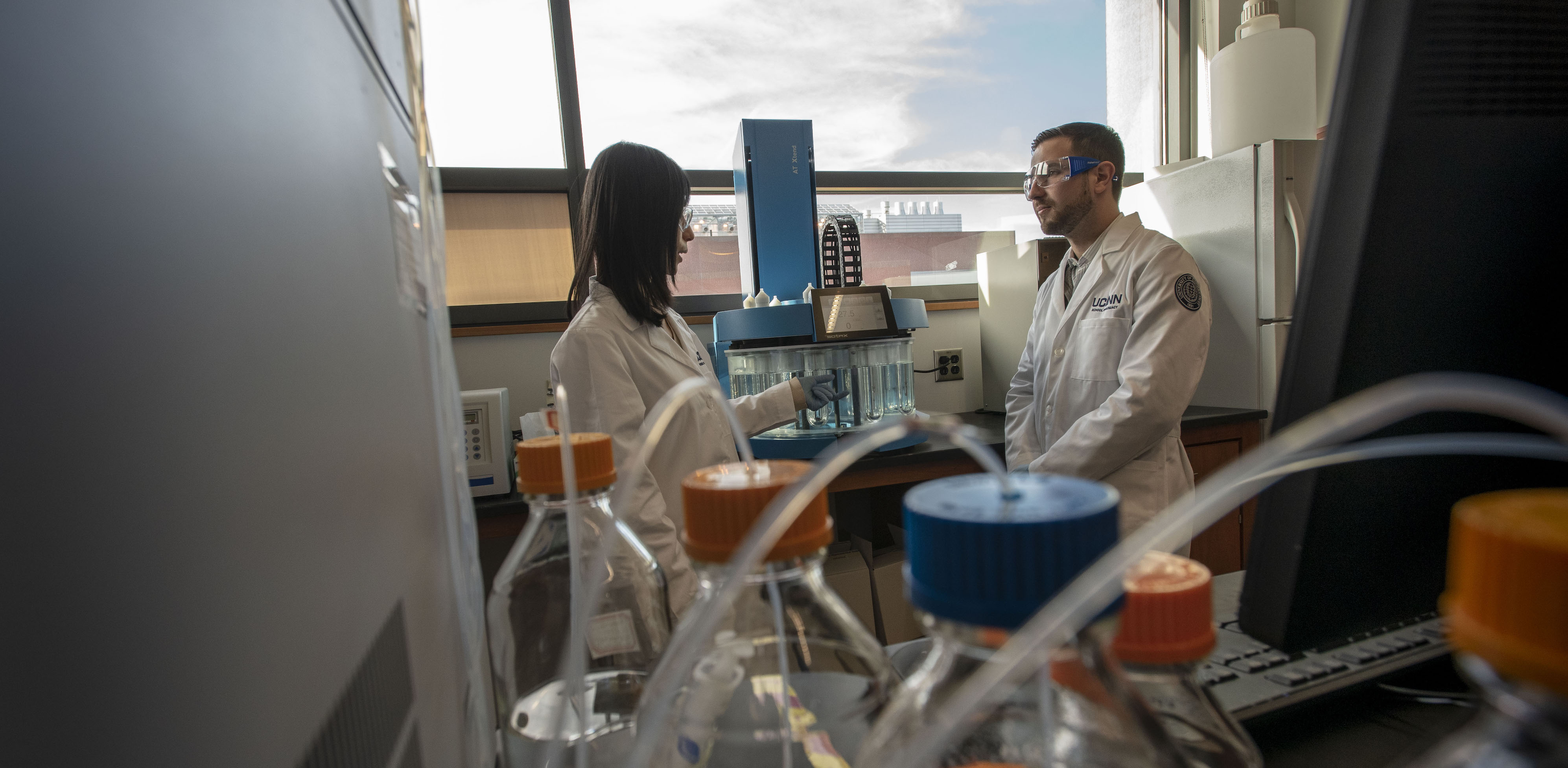 Faculty member Xiuling Lu speaks with a student in a laboratory inside the UConn School of Pharmacy